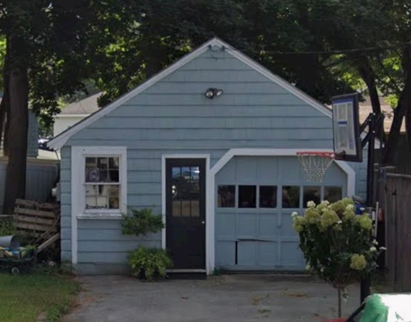 Charming blue cottage with carriage-style garage door and garden landscaping in Massachusetts
